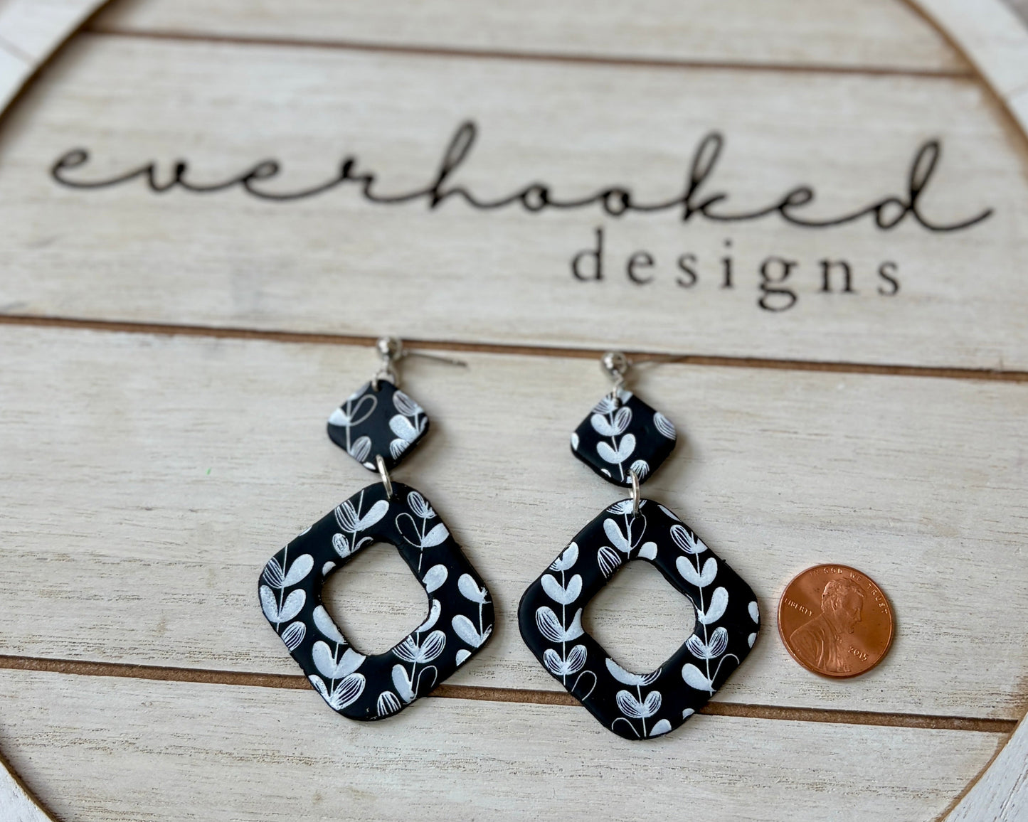 Black and White Floral Two Piece Dangles with penny next to it for sizing