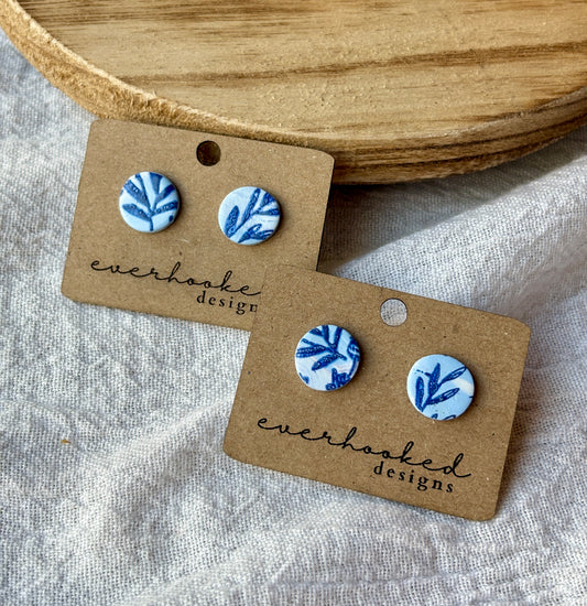 Clay blue stud earrings featuring a painted floral design
