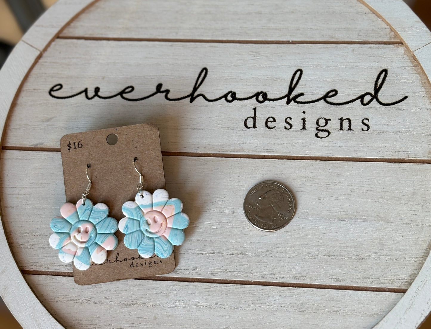 Floral smiley face dangly earrings attached to a silver hook. Quarter in photo for comparison.