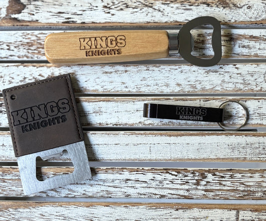 Set of bottle openers with 'KINGS KNIGHTS' branding on a wooden surface.