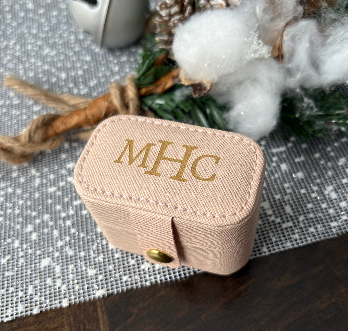 Close-up of custom engraved gold monogram on pink leatherette mini ring box.