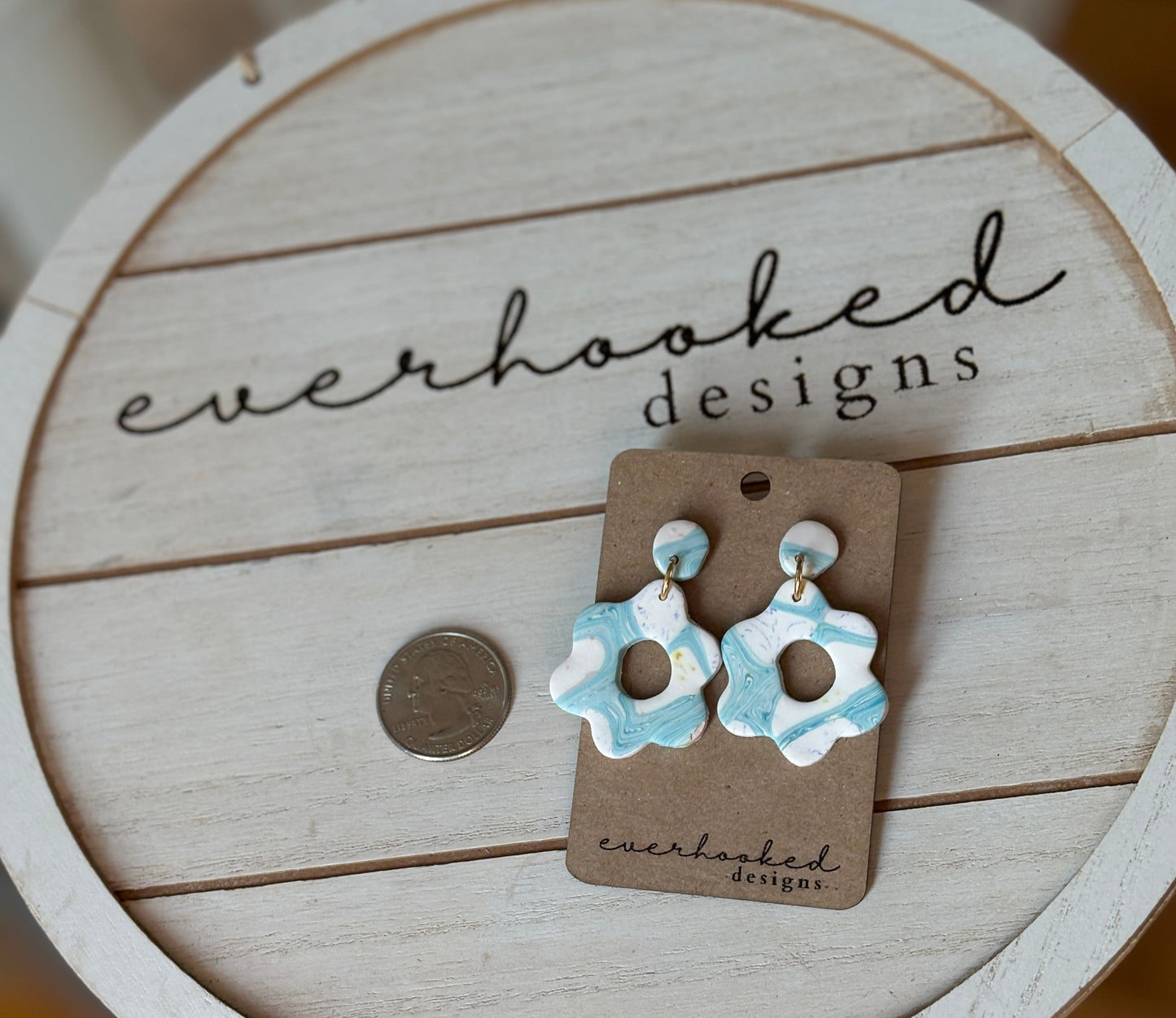 Round floral dangly earrings attached to a stud. Blue and white colors.