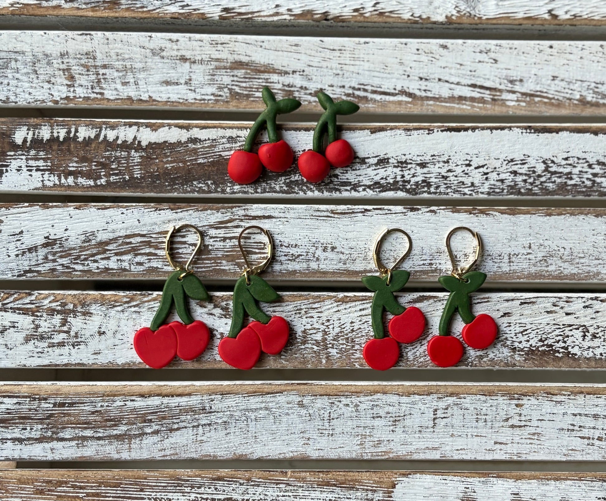 Three variations of adorable cherry earrings, stud earrings, regular cherry dangles, and heart cherry dangles