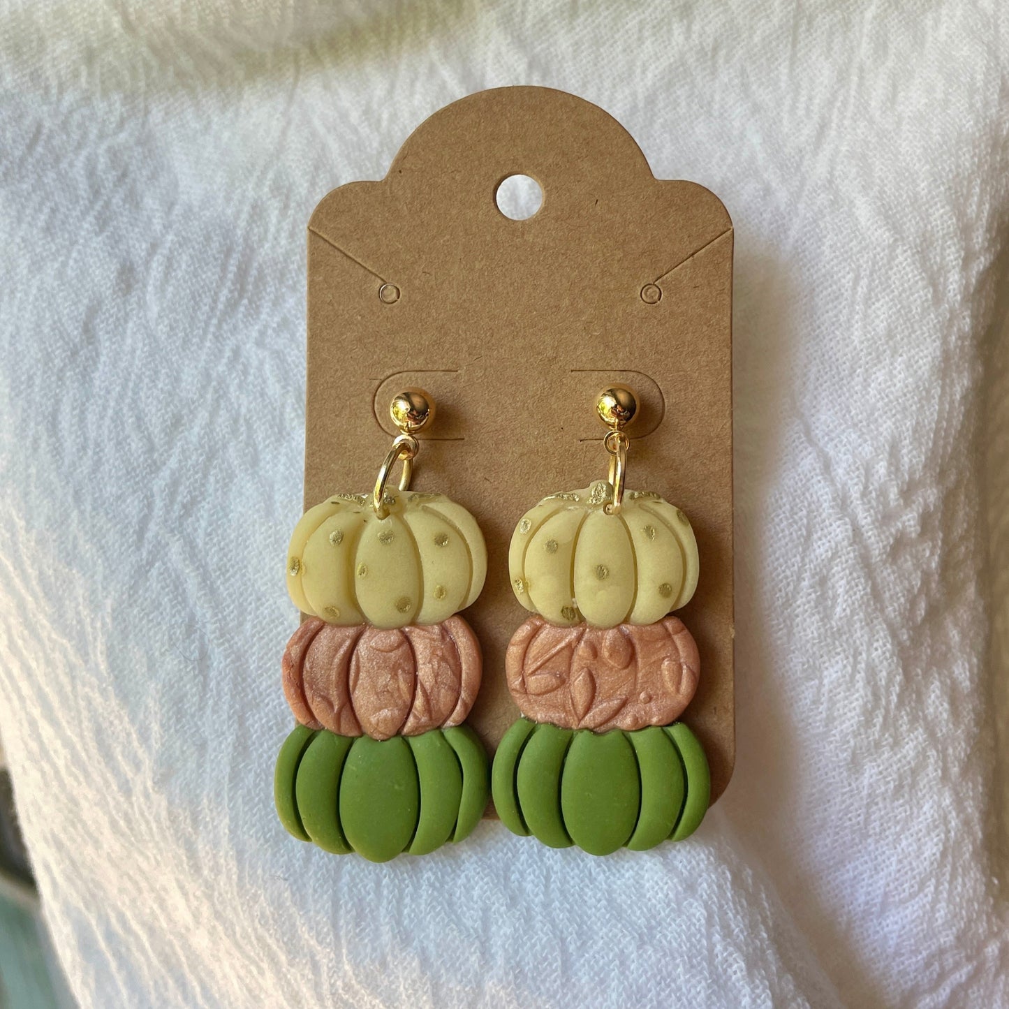 Triple pumpkin earrings layered in different colors and textures
