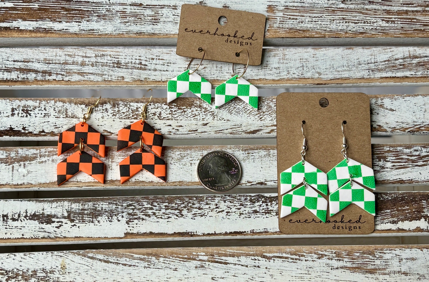 Three pairs of chevron-shaped checkerboard clay earrings in green and white or orange and black, shown with a quarter for size reference. Includes mini hoops and stacked dangles.