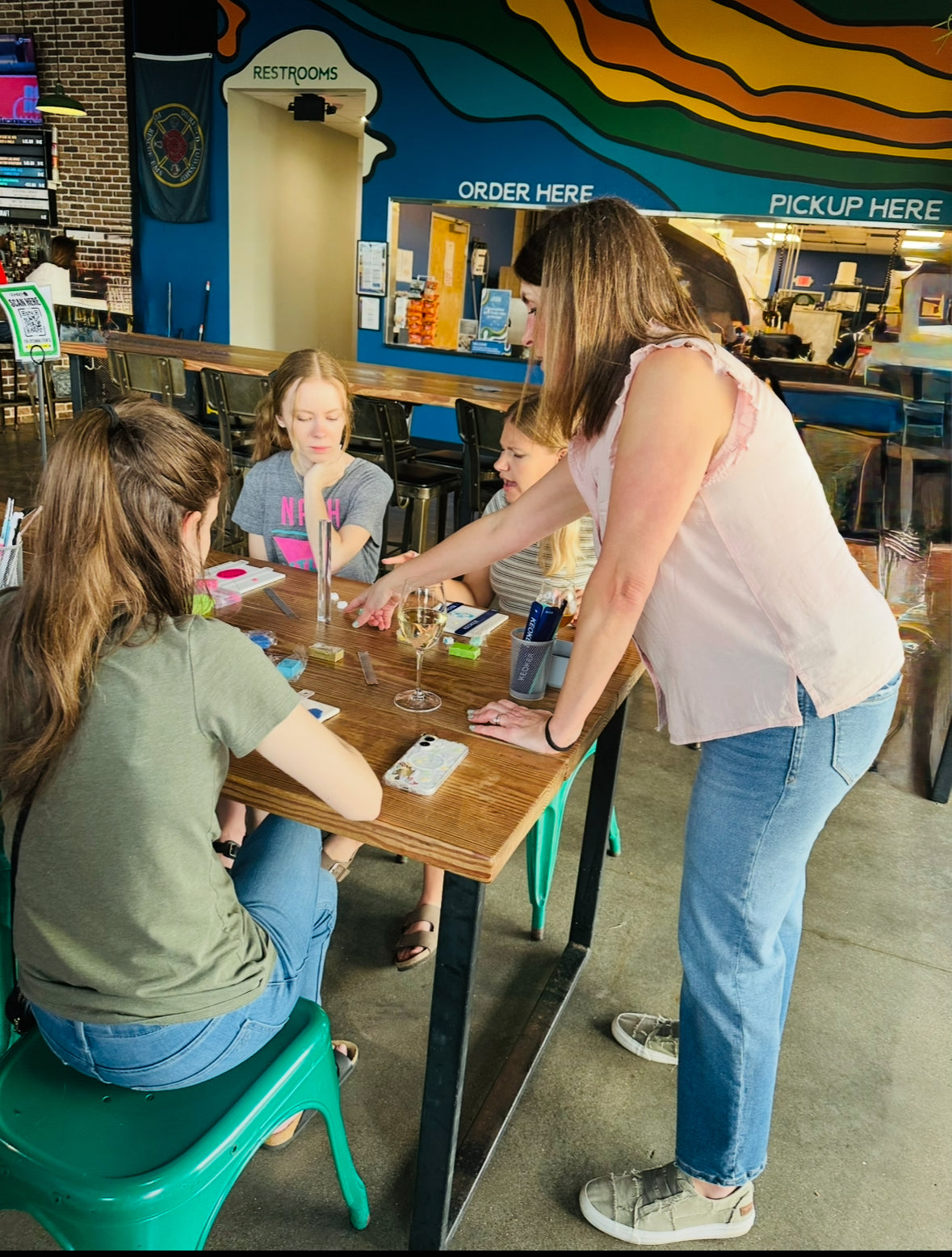 Workshop instructor guiding three attendees through the clay earring process at Sonder Brewing.