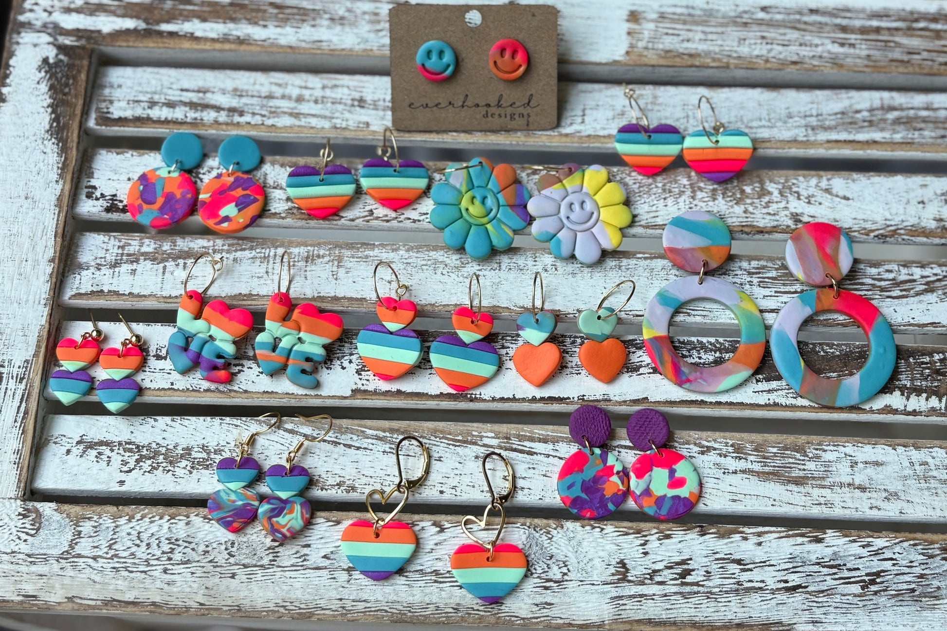 Handmade Pride earrings in rainbow colors, displayed on a white background with bold, bright styles.