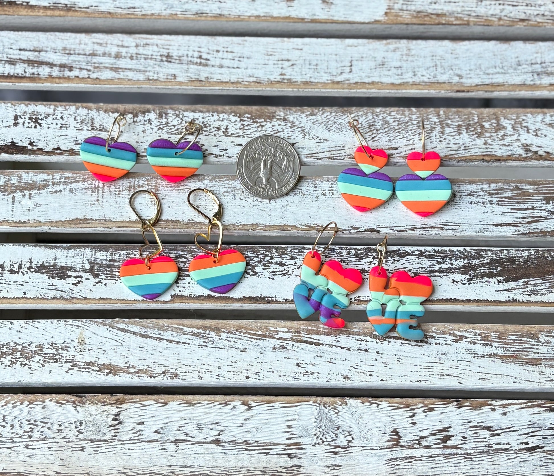 Close-up of rainbow heart dangles and LOVE clay earrings