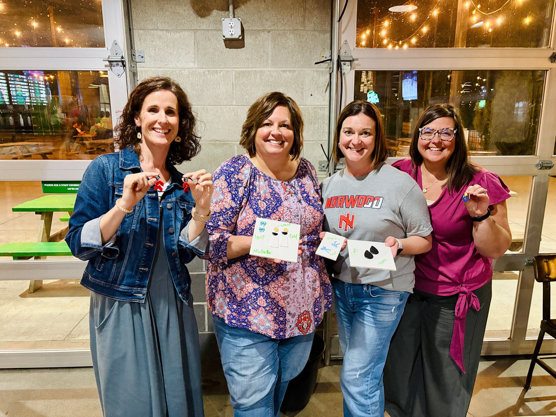 Four smiling guests holding up the earrings they made at the Everhooked clay workshop at Sonder Brewing.