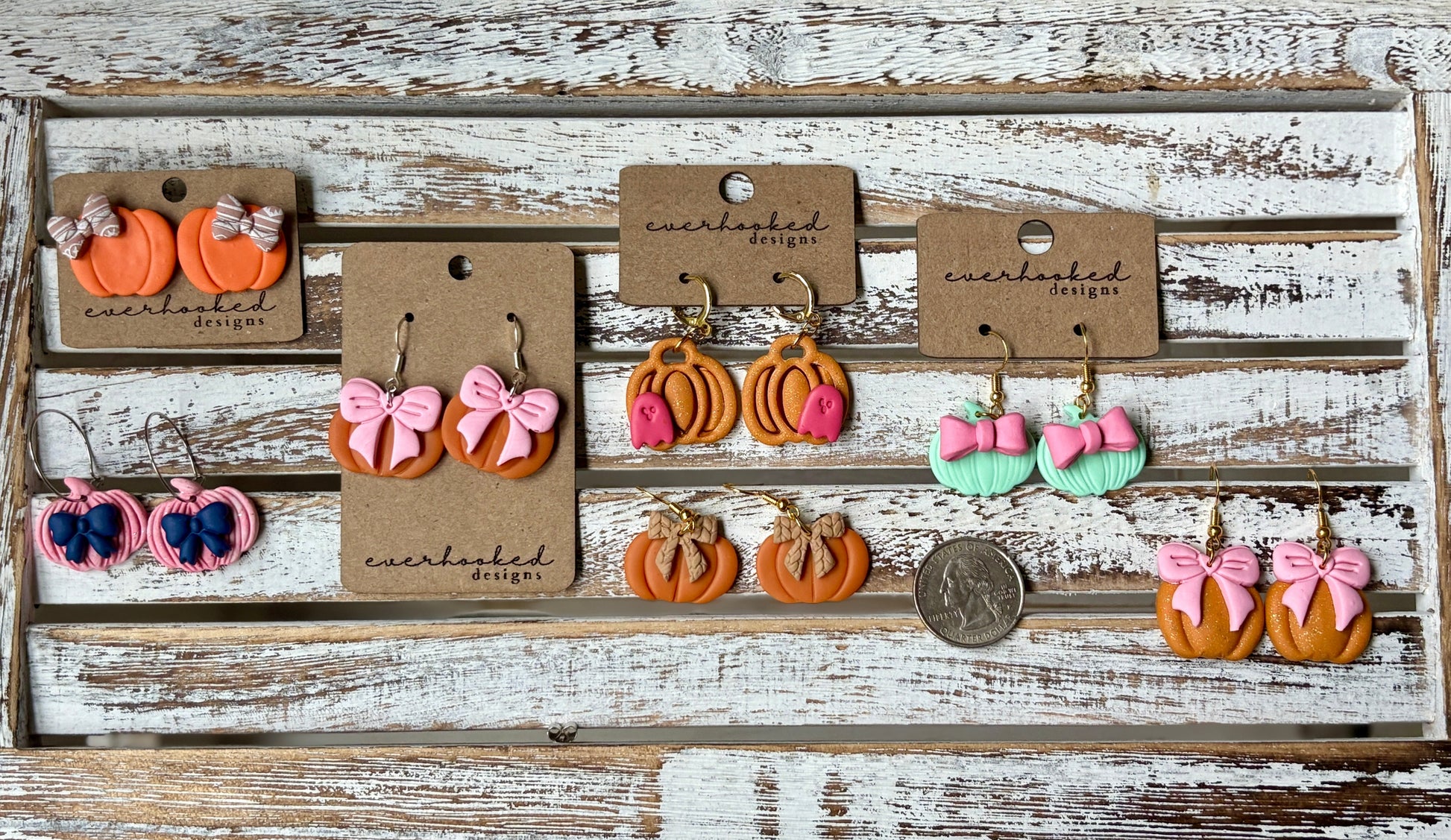 Handmade polymer clay pumpkin earrings in assorted fall styles, including orange, pink, and mint pumpkins with bows and classic designs, lightweight autumn jewelry by Everhooked. Pictured with quarter for sizing