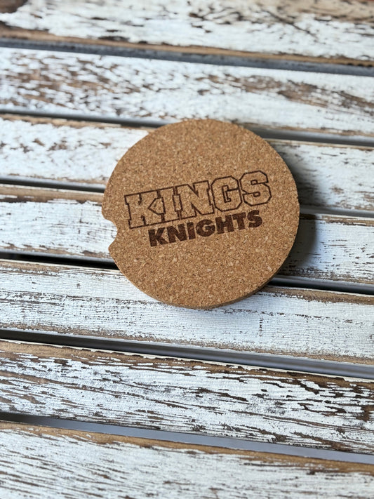 Car cork coaster with 'KINGS KNIGHTS' text on a wooden surface