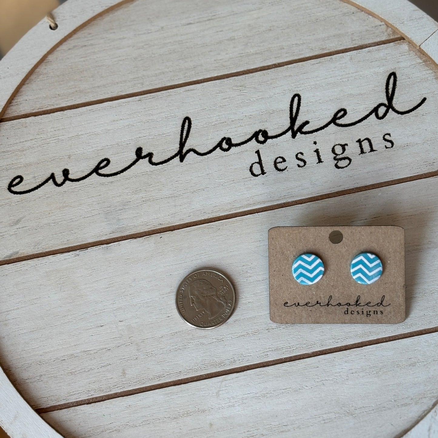 Teal and pink circle chevron stud earrings next to a quarter for size comparison