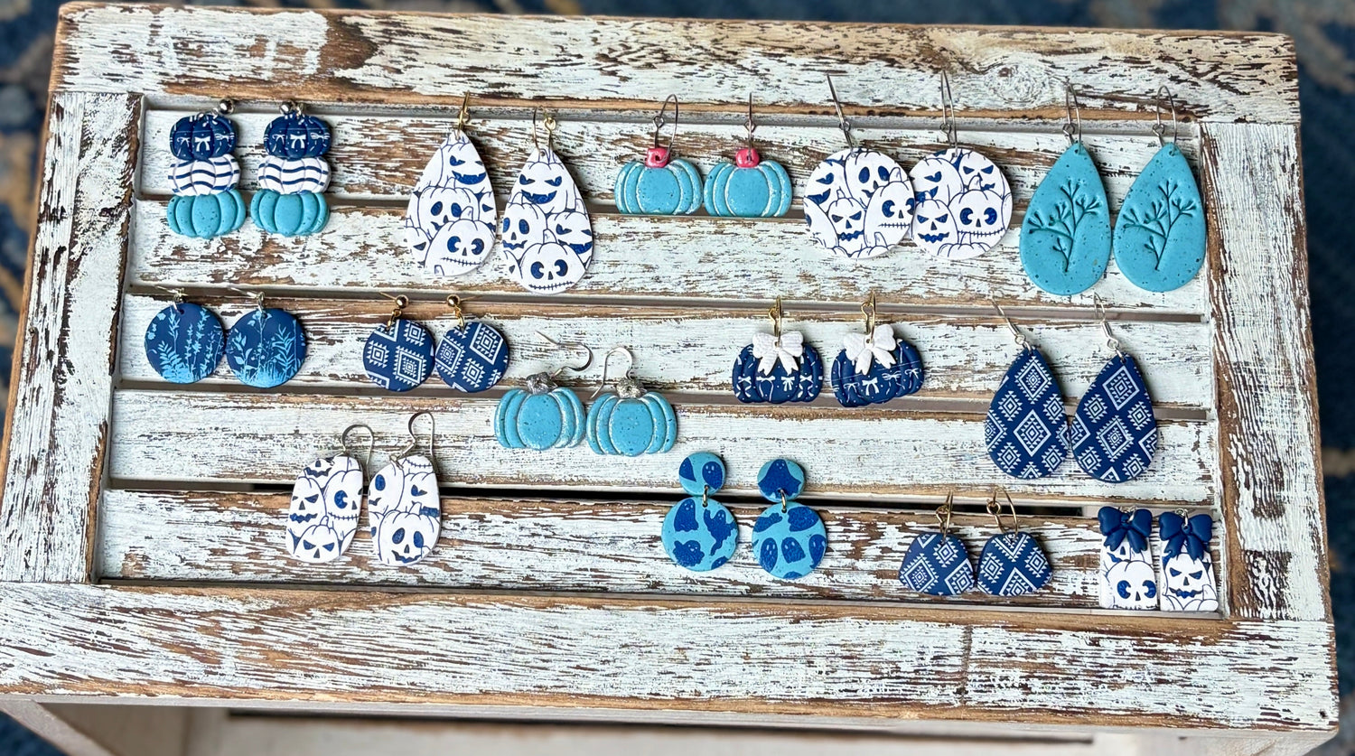 feeling blue fall collection of handmade polymer clay earrings on rustic wood display