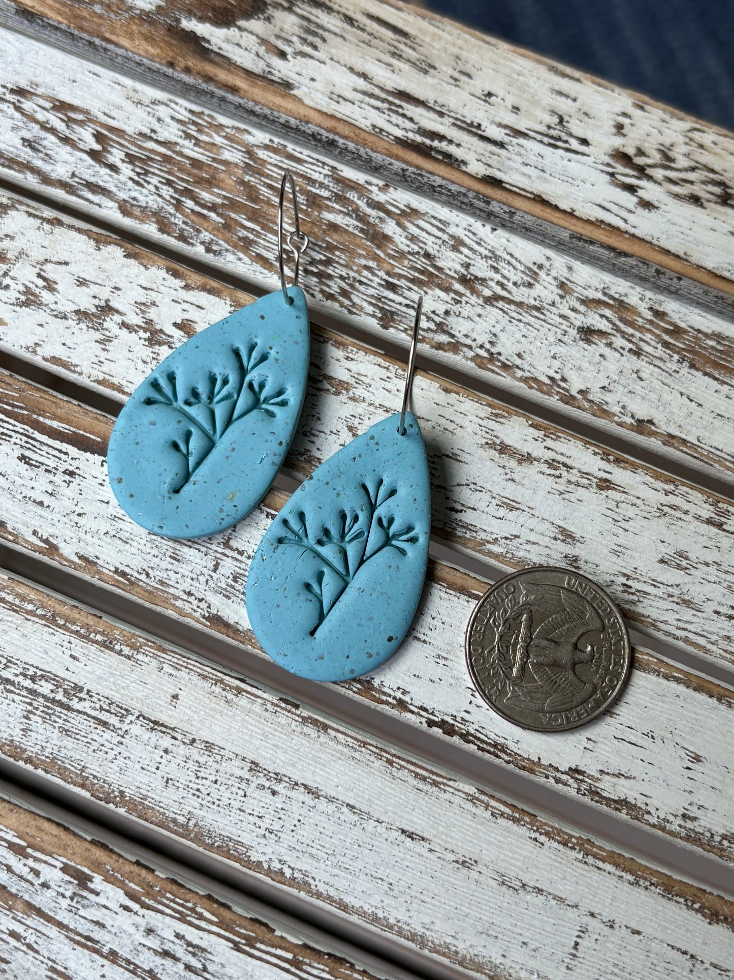Handmade light blue teardrop earrings with embossed botanical design